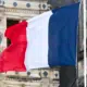 Drapeau français flottant sur un bâtiment public, symbole des sociétés publiques locales